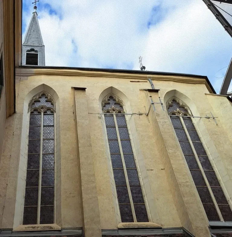Blick im Innenhof auf die Kirchenfenster und den Glockenturm, sowie ein Kreuz