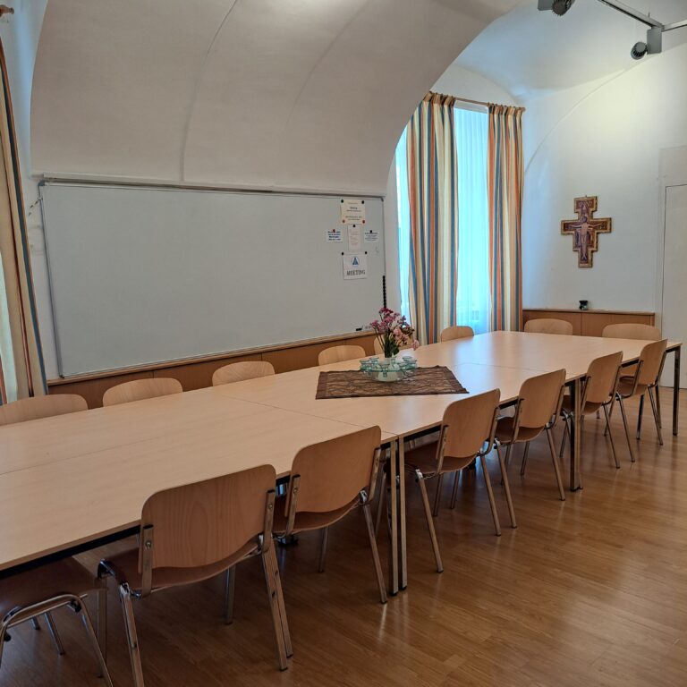 im Gemeindeheim findet man auch eine große Magnettafel und eine Pinwand, es sind 3 große Tische und 15 Sessel aufgestellt, Sitzplätze erweiterbar, ein Kreuz hängt an der Wand
